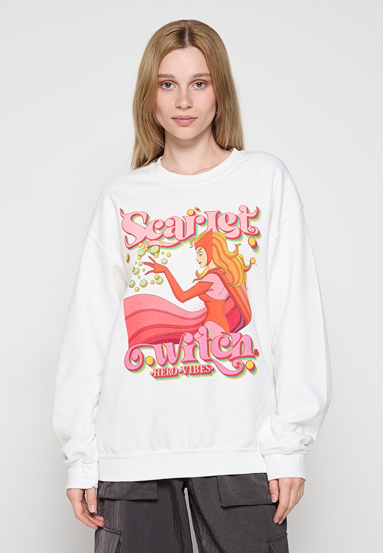 Vit sweatshirt med en färgglad grafik av en karaktär med långt rött hår, som bär en flödande rosa klänning och texten "Scarlet Witch."