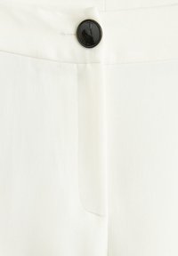 Białe spodnie o gładkiej fakturze, z czarnym guzikiem i przednią kieszenią. Dopasowany krój z starannymi detalami szwów.