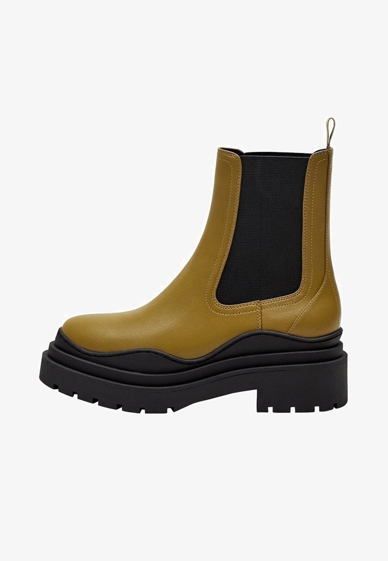 Bottine en cuir vert olive avec semelle plateforme noire épaisse et panneau élastique sur le côté, avec une languette à l'arrière.