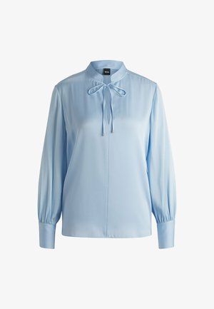 Jasnoniebieska bluzka z długim rękawem, z kołnierzykiem stójkowym, zawiązywanym detalem przy szyi, gładkim materiałem i pełnymi rękawami przy mankietach.