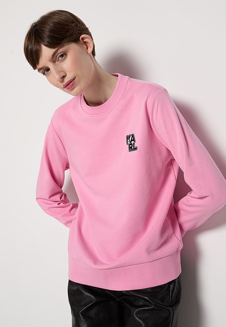 Rosa Sweatshirt aus weichem Stoff, mit rundem Halsausschnitt, langen Ärmeln und einem kleinen schwarzen "KARL"-Logo auf der linken Brust. Glatte Textur.