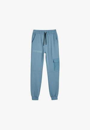 Lyseblå joggingbukser med elastisk talje, snøre, to sidelommer og en cargo-lomme, med trykt tekst på venstre ben.
