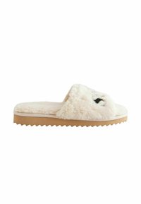 Fuzzy flødefarvet slidesandal med åben tå, struktureret overdel, gummisål og zigzag kant. Har et diskret ansigt design foran.
