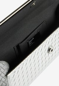 Clutch intrecciato argento con chiusura a scatto, che rivela un interno nero e un'etichetta con la scritta "amici come questi."
