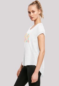 White short-sleeve t-shirt with a slight high-low hem. Features colorful text on the front. Fabric appears soft with a lightweight texture.