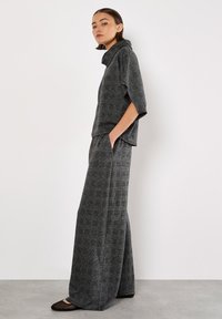 Gråternet loungewear sæt med top i funnel neck og vide bukser. Blød, struktureret stof med lommer på bukserne.