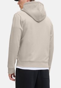 Beige Kapuzenpullover mit langen Ärmeln, ausgestattet mit einer Kängurutasche und gerippten Bündchen. Weicher Stoff, lockere Passform und dezente Textur.