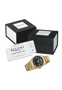 Montre en or avec un cadran noir texturé, des index horaires en argent et un affichage de date, accompagnée de deux boîtes noires avec le logo "REGENT".