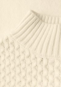 Biały sweter dzianinowy z teksturowanym wzorem i ryflowanym kołnierzem. Tkanina wygląda na miękką i puszystą, z subtelnymi wariacjami w grubości włóczki.