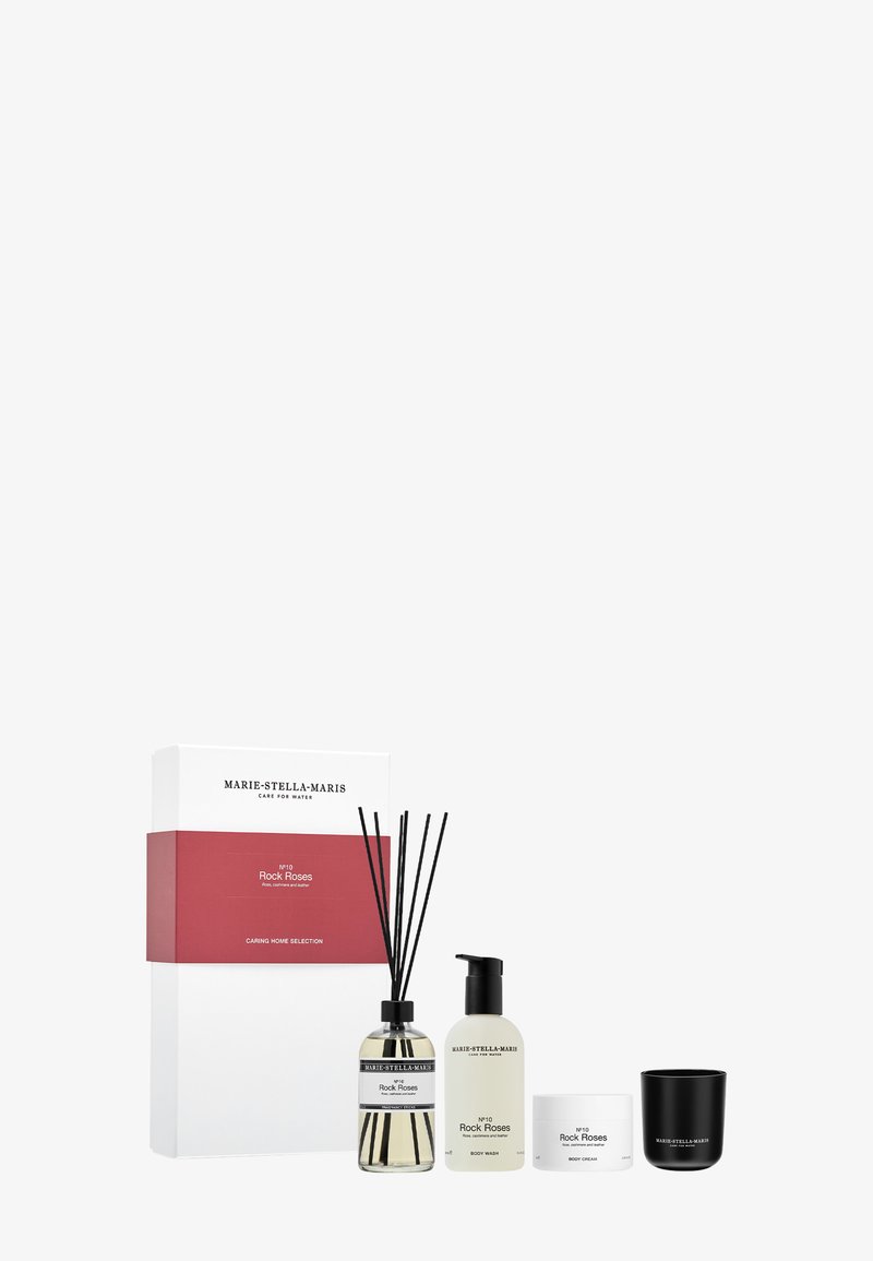Coffret cadeau comprenant un diffuseur rayé avec des roseaux noirs, un gel douche, une crème pour le corps et une bougie noire. Emballé dans une boîte blanche avec des accents rouges.
