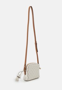 Sac bandoulière en textile beige clair avec un extérieur à motifs, une sangle en cuir brun et un détail de pompon décoratif. Il est doté d'une fermeture éclair.