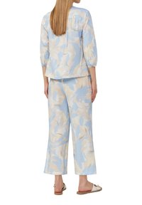 Ensemble léger et texturé en deux pièces dans des tons pastel bleu et crème, présentant des motifs abstraits, une coupe ample, des manches trois-quarts et un pantalon large.