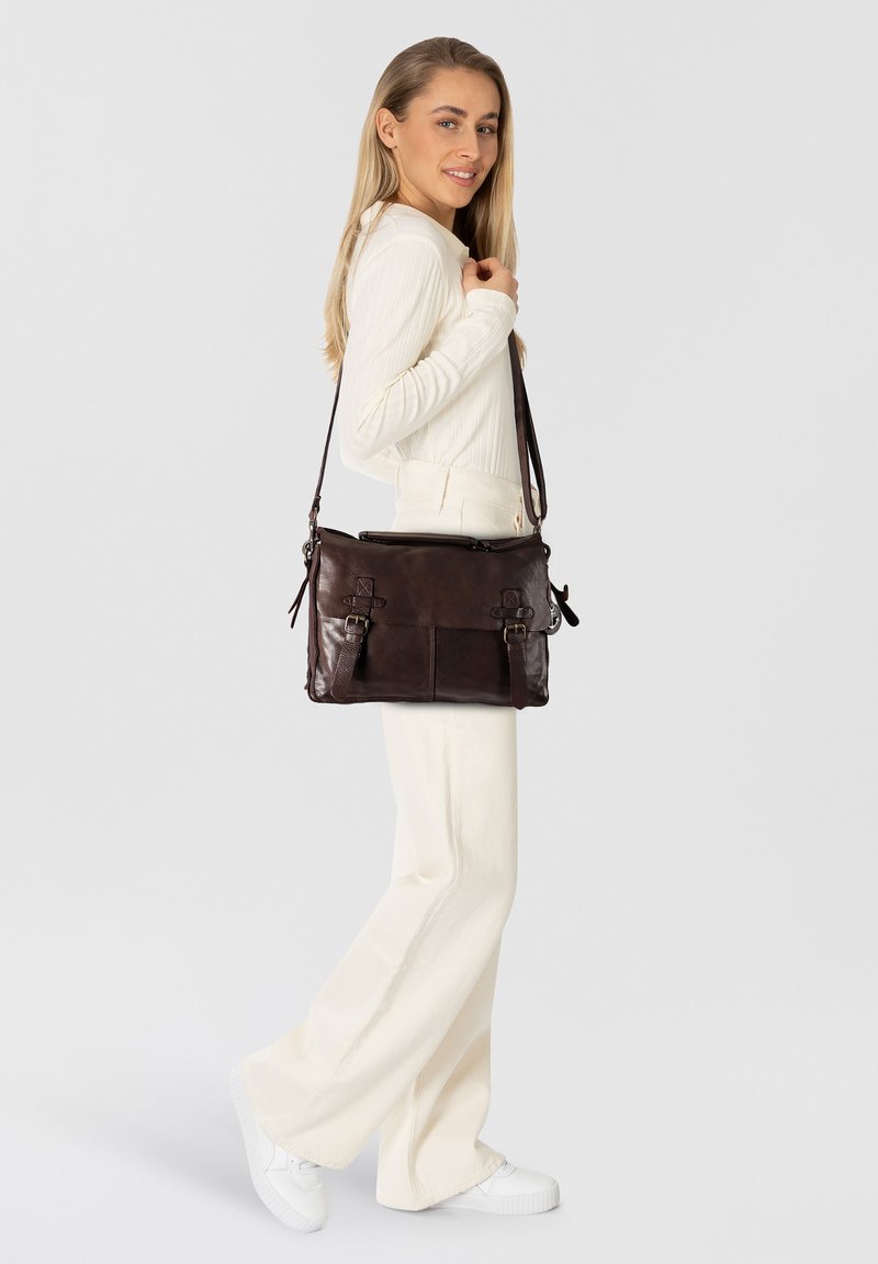 Bolso mensajero de cuero marrón oscuro con acentos de doble hebilla, asa superior, correa ajustable y dos bolsillos frontales. Textura suave, forma rectangular.