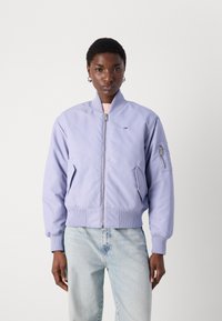 Ljubičasta bomber jakna s rebrastim manžetama i rubom, s prednjim zatvaračem i bočnim džepovima. Mali logo detalj na prsima i džepu na rukavu.