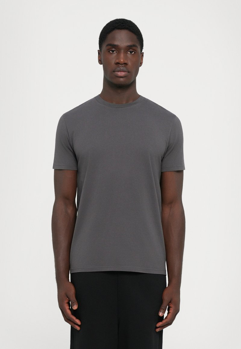 Grijze T-shirt met korte mouwen, gemaakt van zacht materiaal, met een ronde halslijn en een ontspannen pasvorm, gepresenteerd op een model tegen een effen achtergrond.
