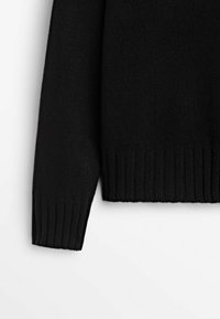 Zwarte trui detail met een gebreide textuur, ronde halslijn en geribbelde manchetten aan de onderkant van de mouwen voor extra elasticiteit.