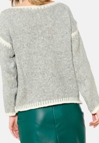Harmaa neulottu villapaita, jossa on leveä off-white kaulus, oversized-malli ja ribattu helma. Tekstuurin näyttää olevan pehmeä ja mukava.