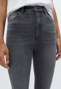 Graue Denim-Jeans mit schmaler Passform, hoch sitzendem Bund und klassischem Fünf-Taschen-Design. Mit dezentem Verblassen und tonalen Nähdetails.