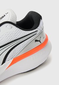 Scarpa da corsa bianca con tomaia in rete testurizzata, accenti neri, branding argentato e intersuola arancione. Presenta la tecnologia di ammortizzazione PROFOAM.