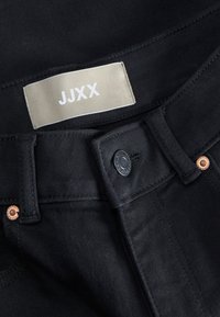 Колан от черен дънков плат с сив етикет на марката JJXX, черен бутон и медни нитове, видими близо до катарамите за колан.