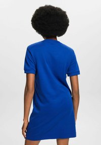 Abito in cotone blu a maniche corte, con vestibilità ampia, scollatura rotonda e orlo che termina appena sopra il ginocchio. Dettagli minimi.