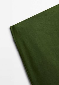 Groene stof met een gladde textuur, licht gekreukt, met een effen kleur en een gedrapeerde hoek, die het lichte materiaal benadrukt.