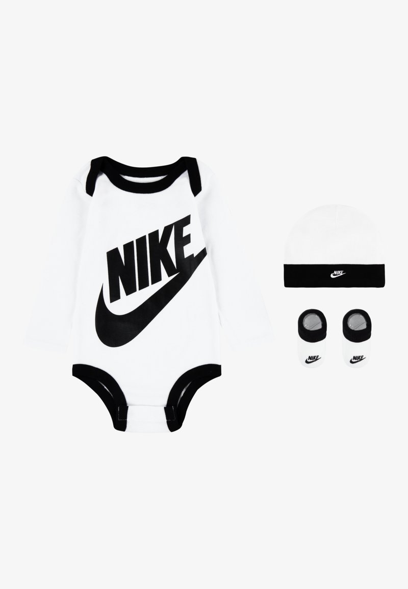 Vit långärmad bodysuit med svarta accenter och en stor svart "NIKE"-logotyp, åtföljd av en matchande svart och vit mössa samt babyskor.