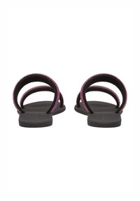 Sandales plates noires avec deux straps courbés ornés d'accents violets, dotées d'une semelle lisse et d'un design minimaliste.