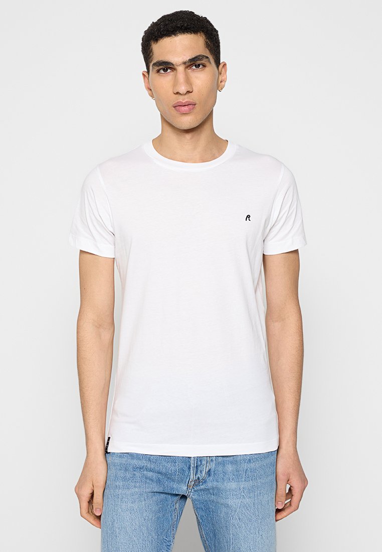 T-shirt en coton blanc avec un col rond et des manches courtes. Présente un petit logo noir sur la poitrine et un design simple.