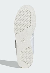 White sneaker sole with a textured surface, featuring a hexagonal pattern for grip and a triangular logo detail at the heel.