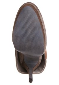 Brązowy zamszowy but na wysokim obcasie o smukłym, zwężającym się kształcie, zaokrąglonym nosku i teksturowanej gumowej podeszwie z poziomymi rowkami.