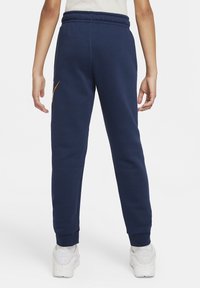 Marina blå sweatpants med en tapered design, elastisk midja och orange logga på övre benet. Tillverkade av mjukt bomullsmaterial.