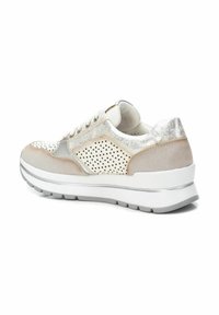 Les baskets arborent un design beige et argenté, avec une tige texturée, des détails perforés et une semelle blanche épaisse pour plus de hauteur.