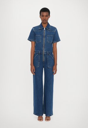 Denim jumpsuit in dark blue. Short sleeves, collar, front zipper, two chest pockets, and wide-leg trousers. Smooth texture and sturdy material.