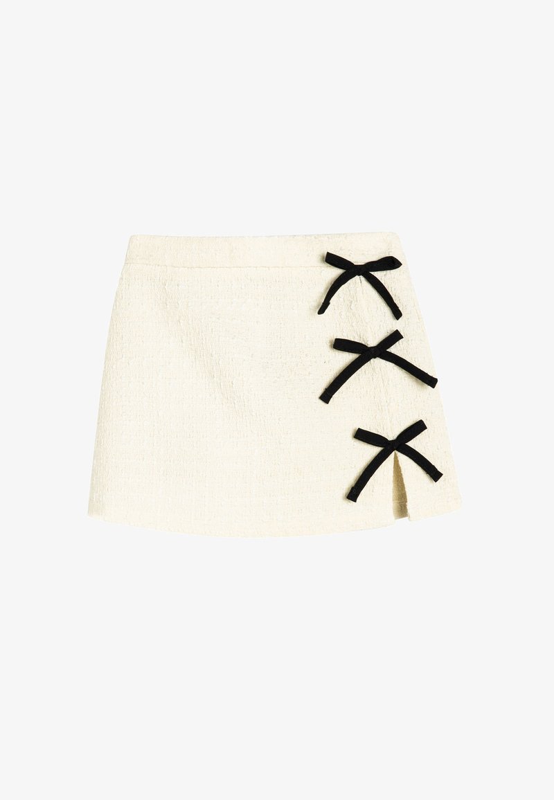 Witte textuur mini rok met drie zwarte lintstrikken aan de zijkant, een asymmetrische zoom en een subtiele splitdetail.