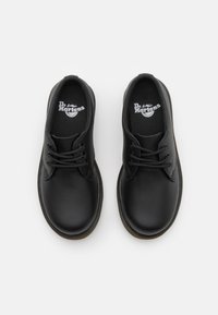 Scarpe in pelle nera con punta tonda, due occhielli per i lacci e una fodera interna testurizzata, dotate di un piccolo logo sulla soletta.