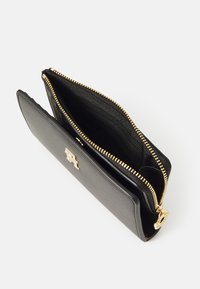 Black leather wallet with a gold zip closure, featuring a textured interior and an embossed logo on the front. Compact and sleek design.