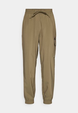 Khaki jogger kalhoty vyrobené z lehkého materiálu, s elastickým pasem, šňůrkou a boční kapsou na cargo. Manžety jsou elastické.
