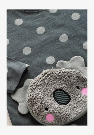 Szürke póló fehér pöttyökkel, plush koala formájú zsebbel, szürke és feketében, rózsaszín részletekkel a szemeknél és az orcáknál.