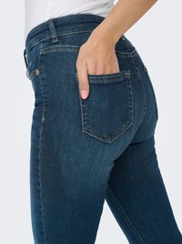 Donkerblauwe denim jeans met een nauwsluitend ontwerp, hoge taille en achterzakken. Heeft subtiele stiksel details en een gladde textuur.