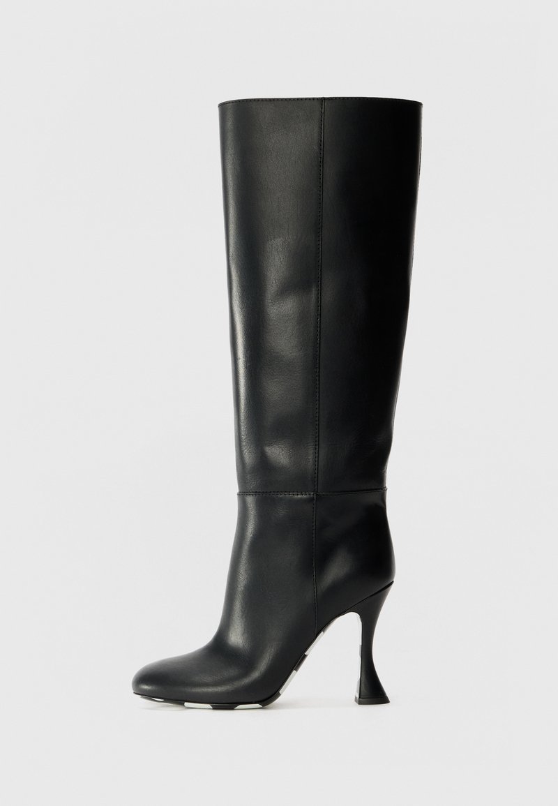 Musta nahkainen polvipituinen saapas, jossa on tiukka varsi ja terävä kärki. Sen huomionarvoinen ominaisuus on kaareva korko ja sileä tekstuuri.