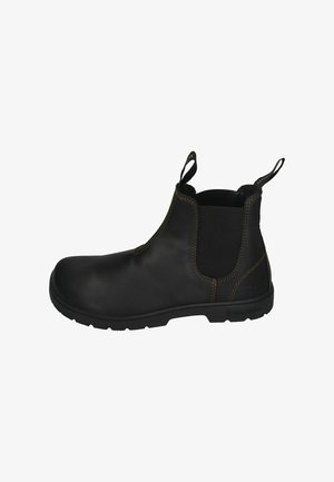 Botín Chelsea de cuero negro con paneles elásticos en los laterales, tiradores, superficie texturizada y costuras claras en contraste. Suela de goma robusta.
