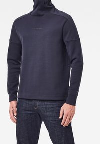 Felpa blu navy con collo alto, maniche lunghe e tessuto testurizzato. Presenta il logo G-Star RAW sul davanti, vestibilità rilassata e polsini a costine.