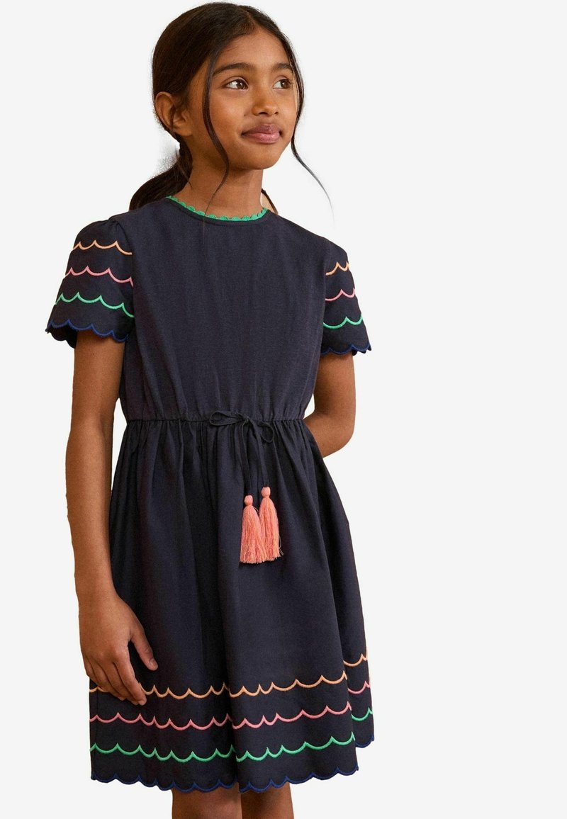 Rochie bleumarin cu mâneci scurte cu margini ondulate, având modele colorate de scoici și ciucuri roz la talie. Fabricată din material ușor.