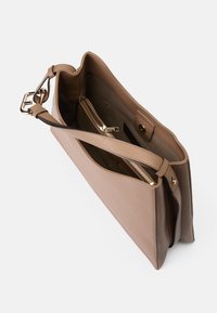 Sac en cuir tan avec une finition lisse, doté d'une bandoulière adjustable, de compartiments zippés et d'une fermeture à pression magnétique.