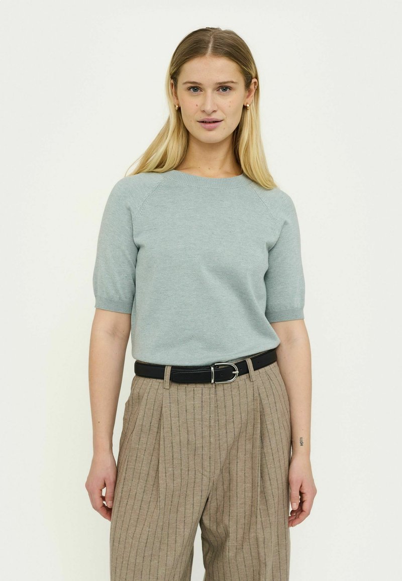 Hellblauer Pullover mit kurzen Ärmeln und rundem Ausschnitt, kombiniert mit beige gestreiften Hosen und einem schwarzen Gürtel, der eine figurbetonte Silhouette schafft.
