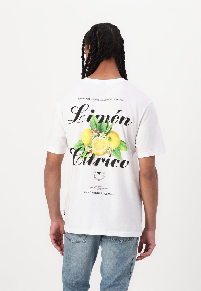 Valkoinen t-paita, jossa on sitruunagrafiikka vihreillä lehdillä, musta teksti "Limón" ja "Cítrico" sekä ylimmässä osassa kuvitusta oleva lisäteksti.
