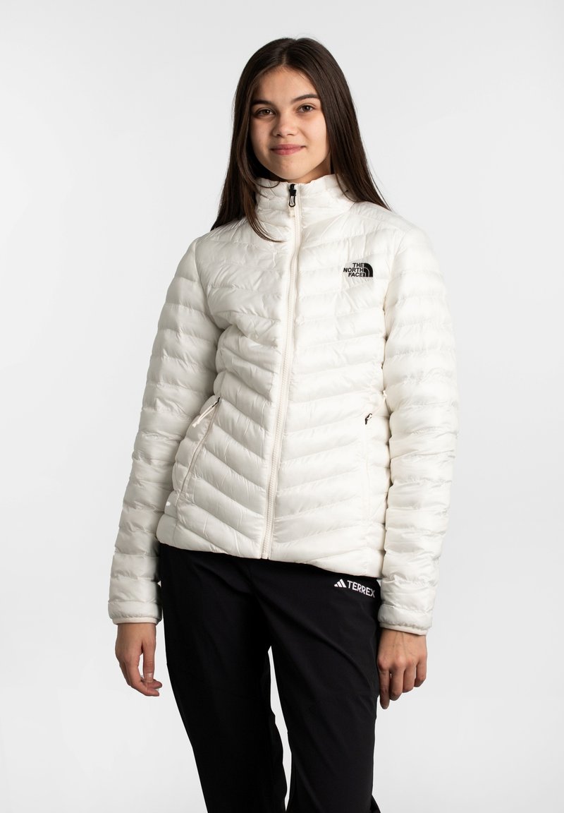 Weiße, isolierte Daunenjacke mit vertikalem Steppmuster, hohem Kragen und Reißverschluss auf der Vorderseite. Mit kleinem schwarzem Logo auf der Brust.