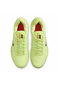 Scarpe sportive di colore giallo neon con tomaia in mesh traspirante, lacci piatti e dettagli rossi sulla linguetta e sulle foderature. Presentano un design elegante e una suola texture.