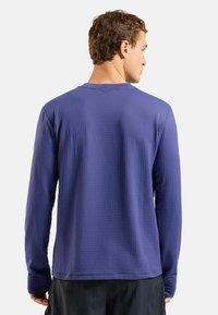 Langärmeliges lila Shirt aus strukturiertem Stoff mit Rundhalsausschnitt. Verfügt über eine lockere Passform und eine glatte Naht entlang der Nähte.